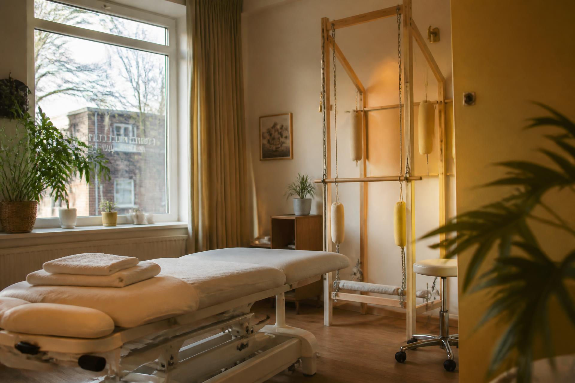 Warm beleuchteter Behandlungsraum mit Behandlungsliege und Schlingentisch